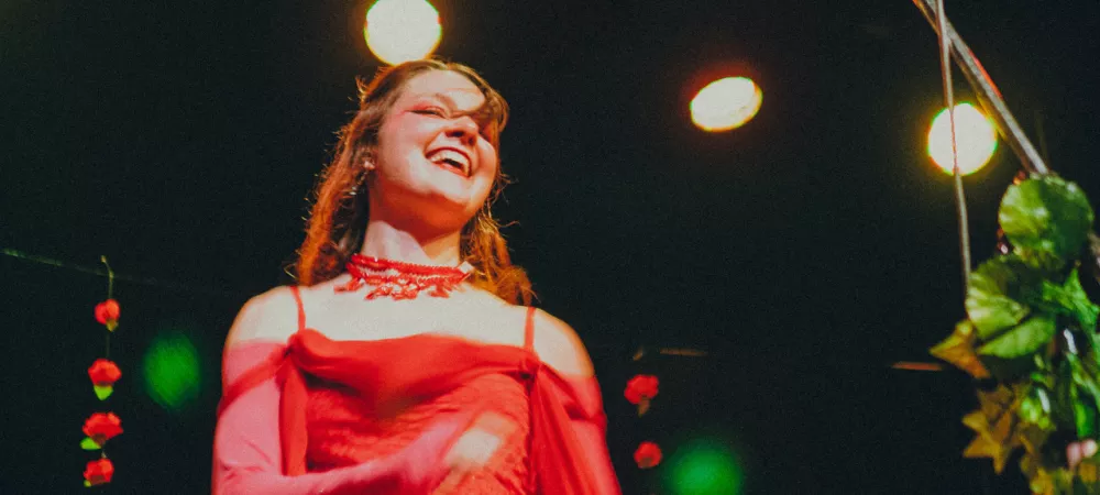 Mujer vestida de rojo y rosa bailando y sonriendo